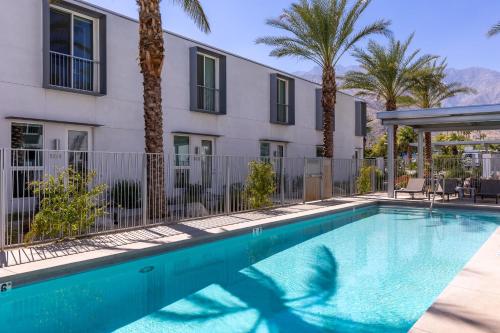 a swimming pool in front of a building with palm trees at House of Light by ACME House Company in Palm Springs