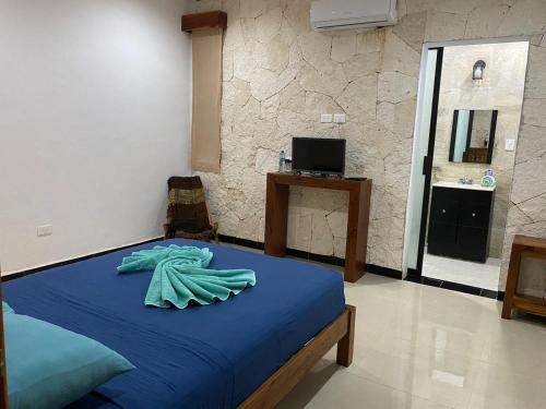 a bedroom with a bed with a blue blanket at Hotel Itza Coba in Cobá
