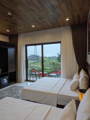 a bedroom with two beds and a large window at Daisy's Villa TamCoc in Vũ Lâm