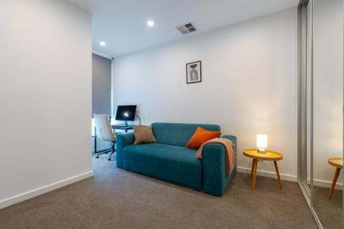 a living room with a blue couch and a table at Modern 3BR Townhouse Near Adelaide CBD Workspace & Parking in Bowden