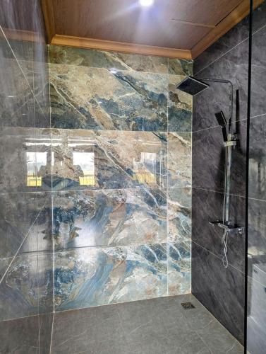 a bathroom with a shower with a stone wall at Daisy's Villa TamCoc in Vũ Lâm
