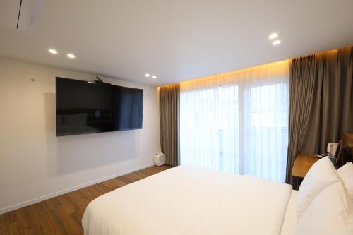 a bedroom with a white bed and a large window at Hotel Onna Haeundae in Busan