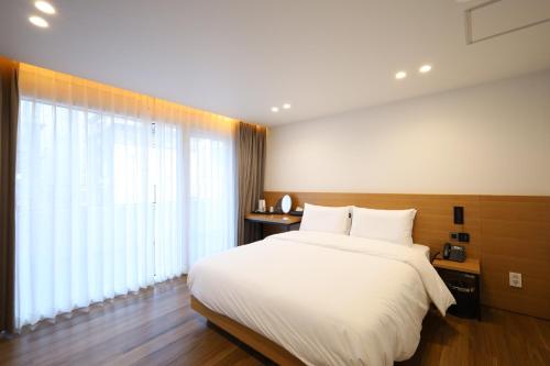 a bedroom with a white bed and a large window at Hotel Onna Haeundae in Busan