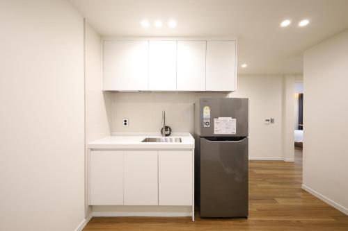 a kitchen with white cabinets and a stainless steel refrigerator at Hotel Onna Haeundae in Busan