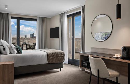 a bedroom with a bed and a desk and a mirror at Leonardo Hotel Vienna City West in Vienna