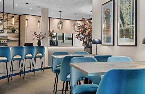 a dining room with blue chairs and tables at Leonardo Hotel Vienna City West in Vienna