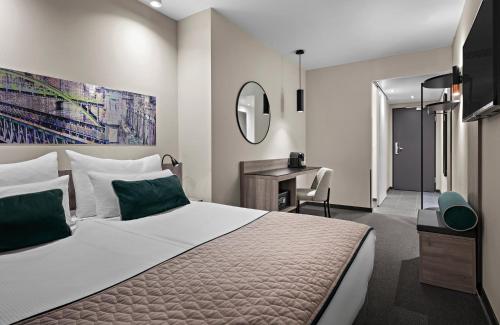 a bedroom with a bed and a desk and a mirror at Leonardo Hotel Vienna City West in Vienna
