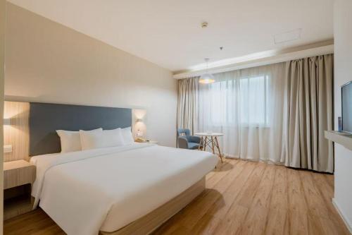 a hotel room with a large white bed and a window at Hanting Hotel Beijing Railway Station Subway Station in Beijing