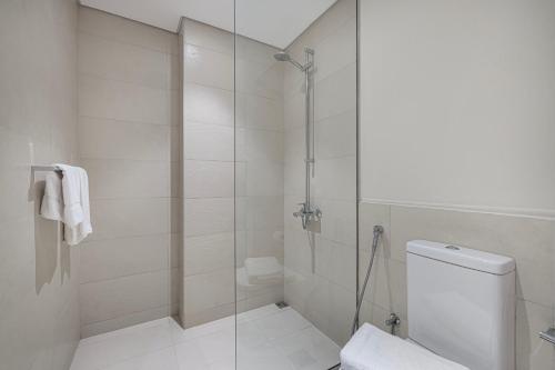 a white bathroom with a shower and a toilet at DVH Luxe Retreats 1BR Yas Island by Ferrari World and Yas Mall in Yas Island