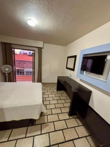 a hotel room with a bed and a flat screen tv at Hotel Plaza in Tepatitlán de Morelos