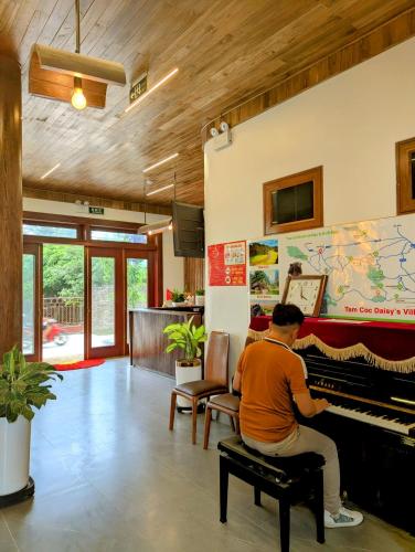 a man sitting on a piano in a living room at Daisy's Villa TamCoc in Vũ Lâm