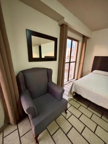 a bedroom with a chair and a bed and a mirror at Hotel Plaza in Tepatitlán de Morelos