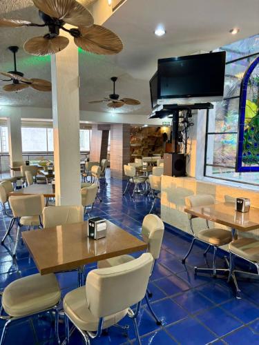 a restaurant with tables and chairs and a flat screen tv at Hotel Plaza in Tepatitlán de Morelos
