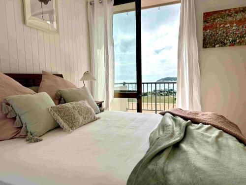 a bedroom with a large bed with a large window at Heavenly Views in Airlie Beach