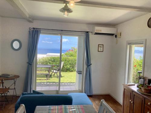 a living room with a blue couch and a sliding glass door at Vacances a la mer Ishigaki in Ishigaki Island