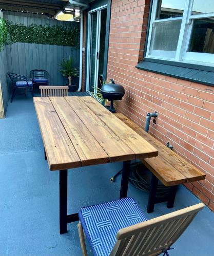 a wooden picnic table sitting next to a brick wall at GREENVIEW, BFast,WiFi,Fetch, Walk2Pizza,Liquor in Bell Post Hill