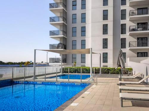 a swimming pool in front of a building at DVH Luxe Retreats 1BR Yas Island by Ferrari World and Yas Mall in Yas Island