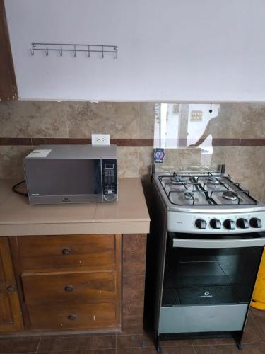 a kitchen with a stove and a microwave at Departamento Familiar La Merced Terracota in Riobamba