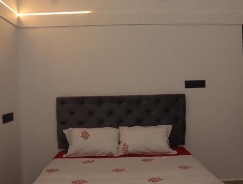 a bed with a black headboard and two pillows at Thazhvaram pool villa calvarymount in Idukki
