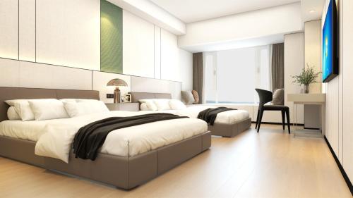 a bedroom with two beds and a desk at Yizhi Hotel Guangzhou Zhujiang New Town US Consulate General Guangzhou Branch - Free Shuttle Bus to Canton Fair Complex During Canton Fair Period in Guangzhou