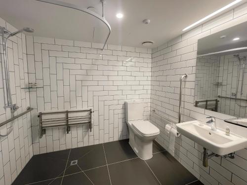 a white bathroom with a toilet and a sink at M Social Auckland in Auckland