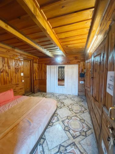 a bedroom with a bed in a room with wooden walls at Oran Stays Shoja in Shoja