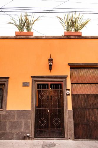 an orange building with two doors and two gates at Casa de hospedaje -La Abadía de San Pedro in Guadalajara