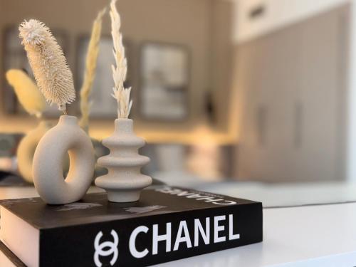 three white vases sitting on top of a book at DVH Luxe Retreats 1BR Yas Island by Ferrari World and Yas Mall in Yas Island