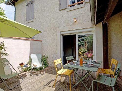 a patio with a table and chairs on a deck at Maison cosy avec terrasse, jardin fleuri, et tout confort à Saint-Galmier - FR-1-496-292 in Saint-Galmier