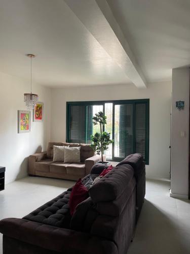 a living room with a brown couch and a large window at Suite em casa familiar in São Gabriel
