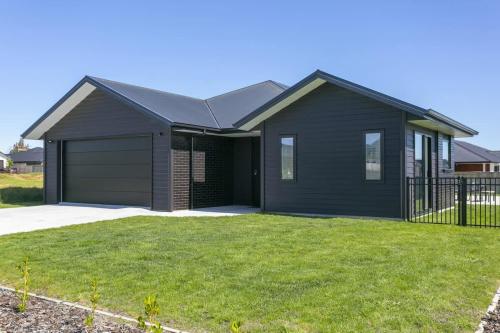 ein schwarzes Haus mit Garage im Garten in der Unterkunft Sophistication Meets Relaxation in Taupo