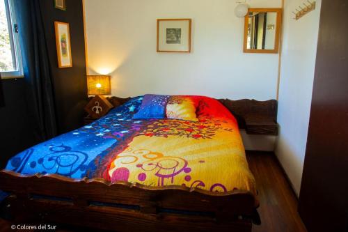 a bedroom with a bed with a colorful comforter at Rosa de los vientos Sur in Coñaripe
