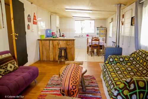 a living room with two couches and a kitchen at Rosa de los vientos Sur in Coñaripe
