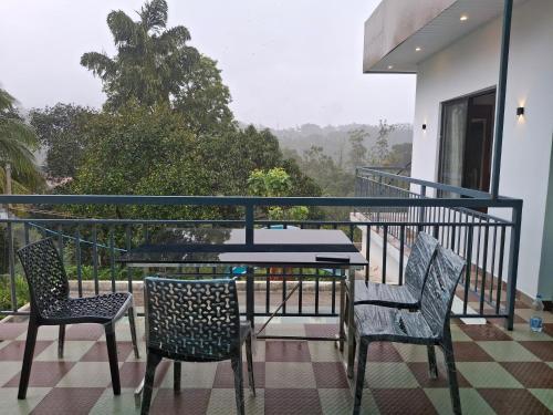 a balcony with two chairs and a table on a balcony at Golden cherry in Munnar