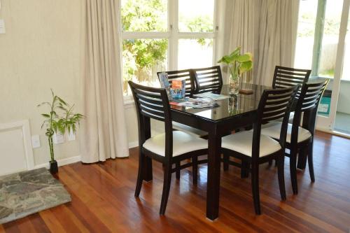 a dining room with a table with chairs and a window at Happiness is Huia a block from the lake in Taupo