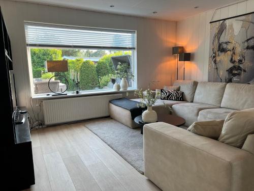 a living room with a couch and a window at Countryside view bungalow near dunes in Sint Maartensvlotbrug