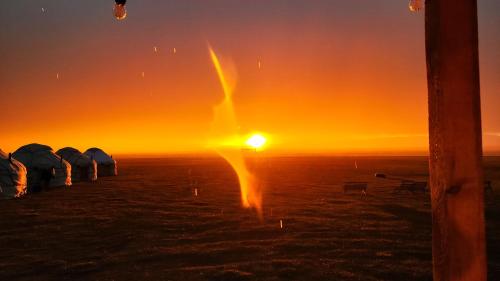 a sunset with a row of tents in a field at Yurt Camp Ali-Nur, Lake Song-Kul , Kyrgyzstan, Юрточный лагерь Али Нур, на берегу озера Сон Кол in Naryn
