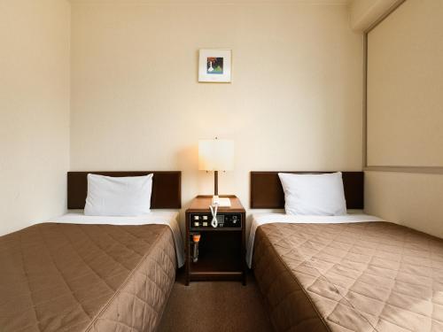 a hotel room with two beds and a table with a lamp at ホテル亀山ヒルズ in Kameyama