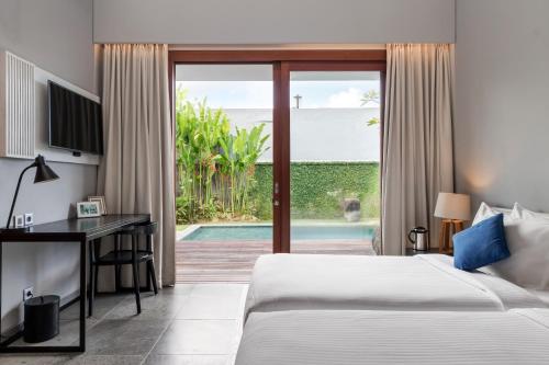 a bedroom with a bed and a desk and a sliding glass door at Amarin Seminyak in Seminyak