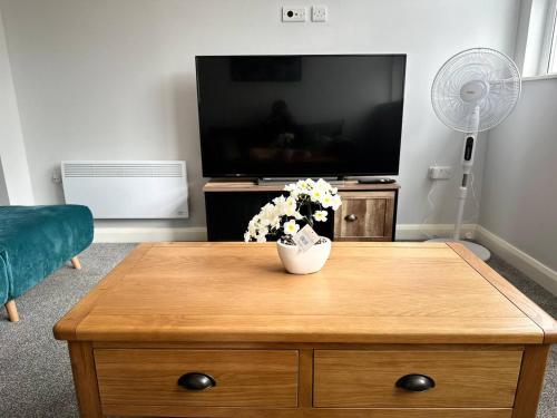 a living room with a tv and a wooden coffee table at Melbourne House Apartment Near Train Station! in Accrington