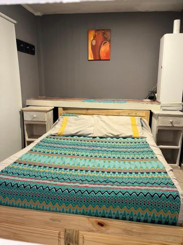 Una cama con edredón en un dormitorio en Camping Los Cardones, en Gobernador Gregores