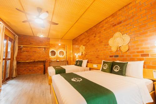 a bedroom with two beds and a brick wall at Mekong Rustic Riverside in Ấp An Nhơn (3)