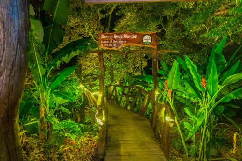 a walkway in a rainforest with a sign and lights at Mekong Rustic Riverside in Ấp An Nhơn (3)