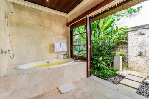 a bathroom with a tub and a large window at Jimbaran Beach Villas by Nakula in Jimbaran