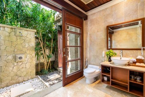 a bathroom with a toilet and a sink and a mirror at Jimbaran Beach Villas by Nakula in Jimbaran