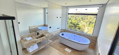 a bathroom with a large tub and a large window at Pousada Alpes Azul in Campos do Jordão