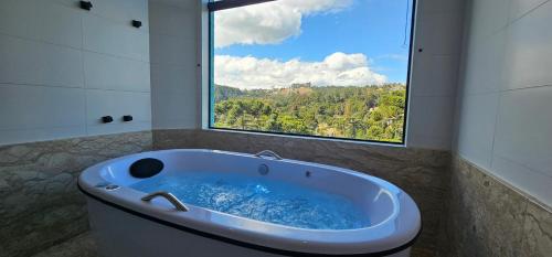 a bath tub in a bathroom with a large window at Pousada Alpes Azul in Campos do Jordão