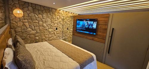 a bedroom with a bed and a tv on a wall at Pousada Alpes Azul in Campos do Jordão