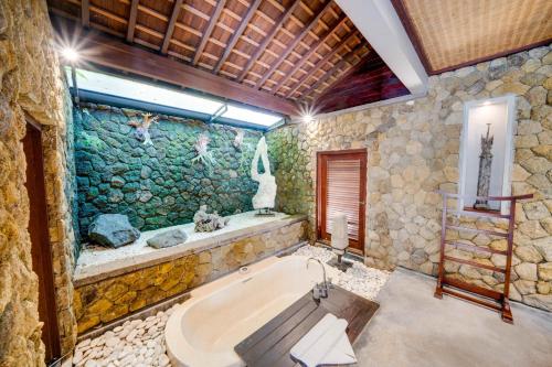 a bathroom with a bath tub with a fish wall at Awan Putih Resort in Payangan
