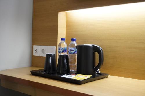 a coffee maker and two bottles of water on a counter at Front One Hotel Papua Lestari in Timika